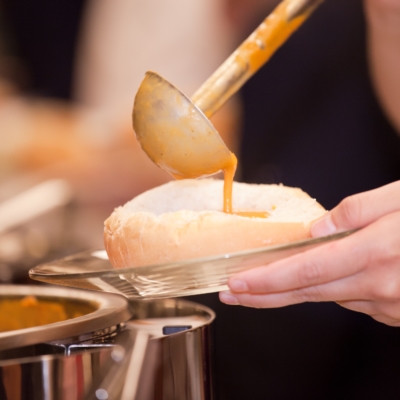 soup being poured into a bread bowl