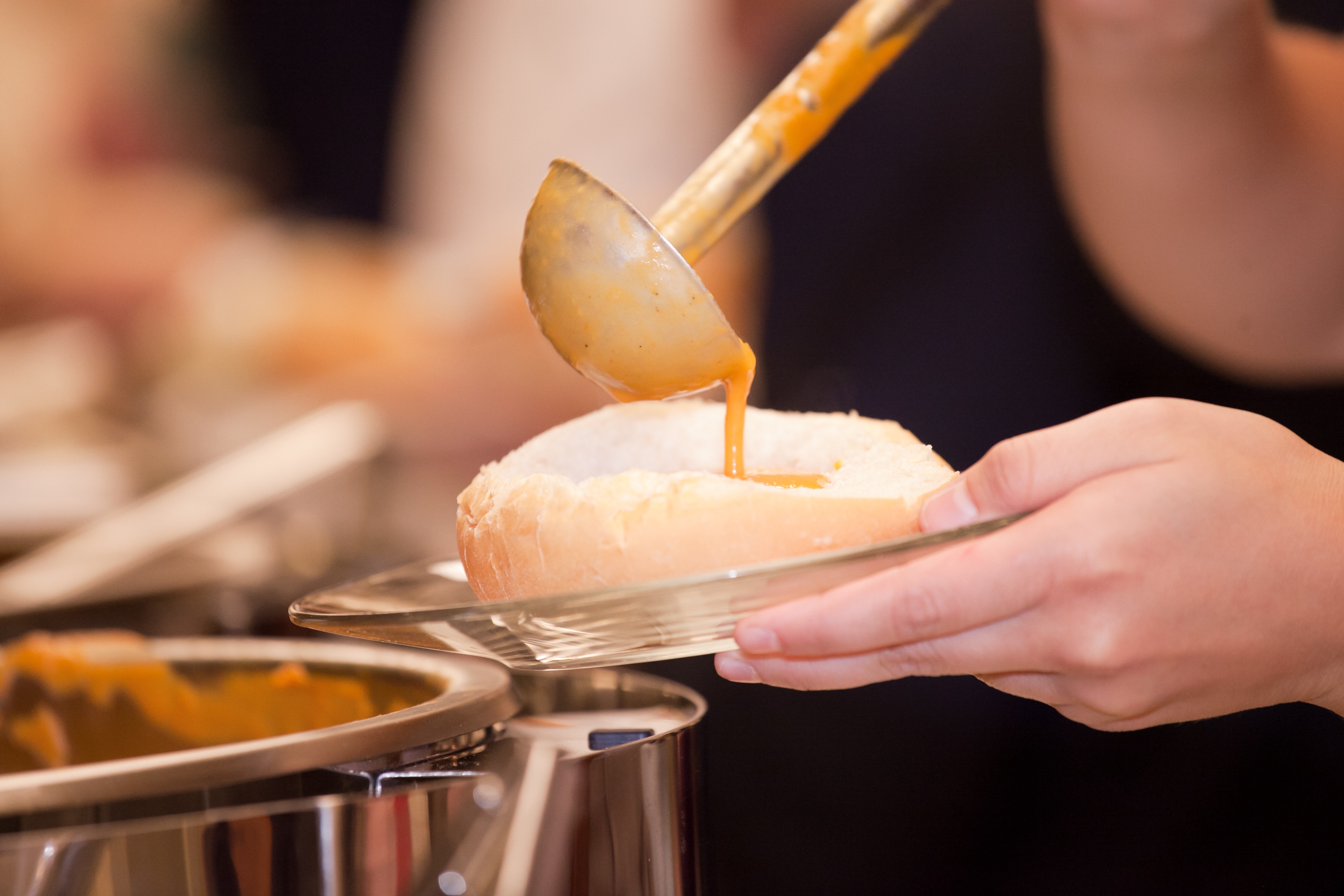 soup being poured into bread bowl