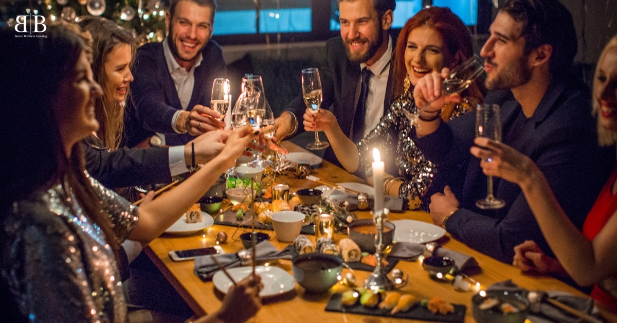 A group of people toasting at a dinner table, enjoying the Ultimate Holiday Feast Solution provided by Brown Brothers Catering in Utah.